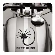 Pegatina de criatura alienígena «FREE HUGS» aplicada sobre un depósito de moto.